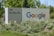 A large sign with 'Google' written in colorful letters is positioned next to '111 W. Java Dr.' The sign is surrounded by green foliage and white flowers, set against a backdrop of trees under clear skies.