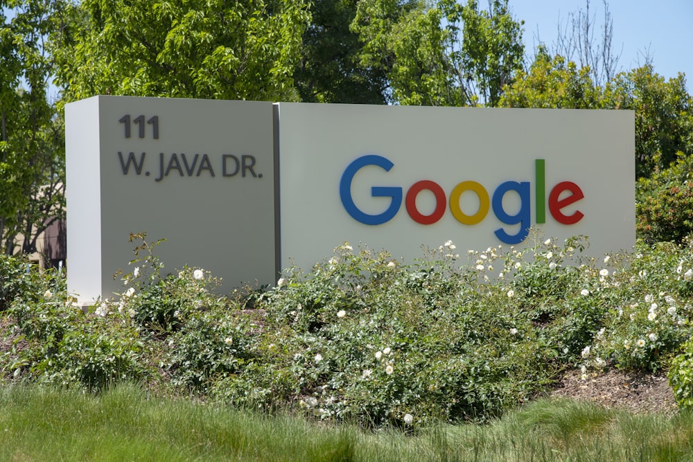 um sinal do Google na frente de alguns arbustos e árvores
