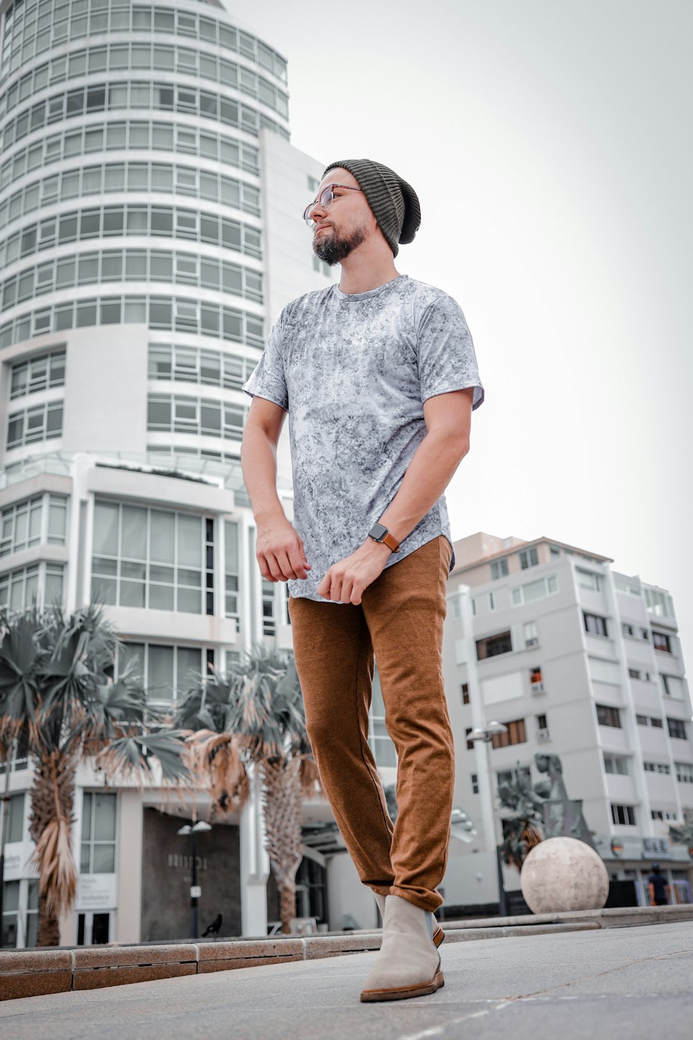 Man in grey crew neck t-shirt and brown pants standing near white concrete  building during photo – Free Clothing Image on Unsplash