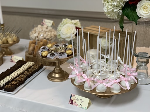Elegant close-up of assorted luxury wedding sweets arranged on a minimalist beige and off-white table with golden accents.