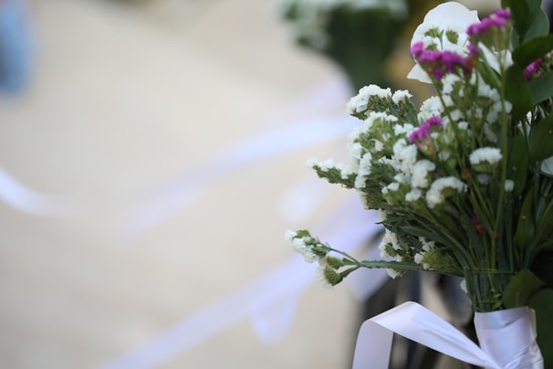 A delicate bouquet of pastel flowers arranged with soft ribbons on a light background.