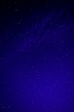 A dark blue night sky filled with bright white stars forming a subtle cross.