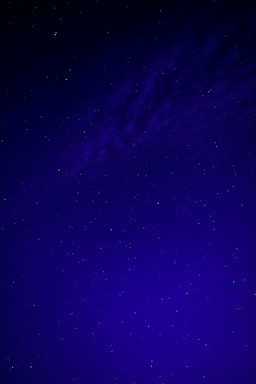 A dark blue night sky filled with bright white stars forming a subtle cross.