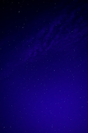 A dark blue night sky filled with bright white stars forming a subtle cross.