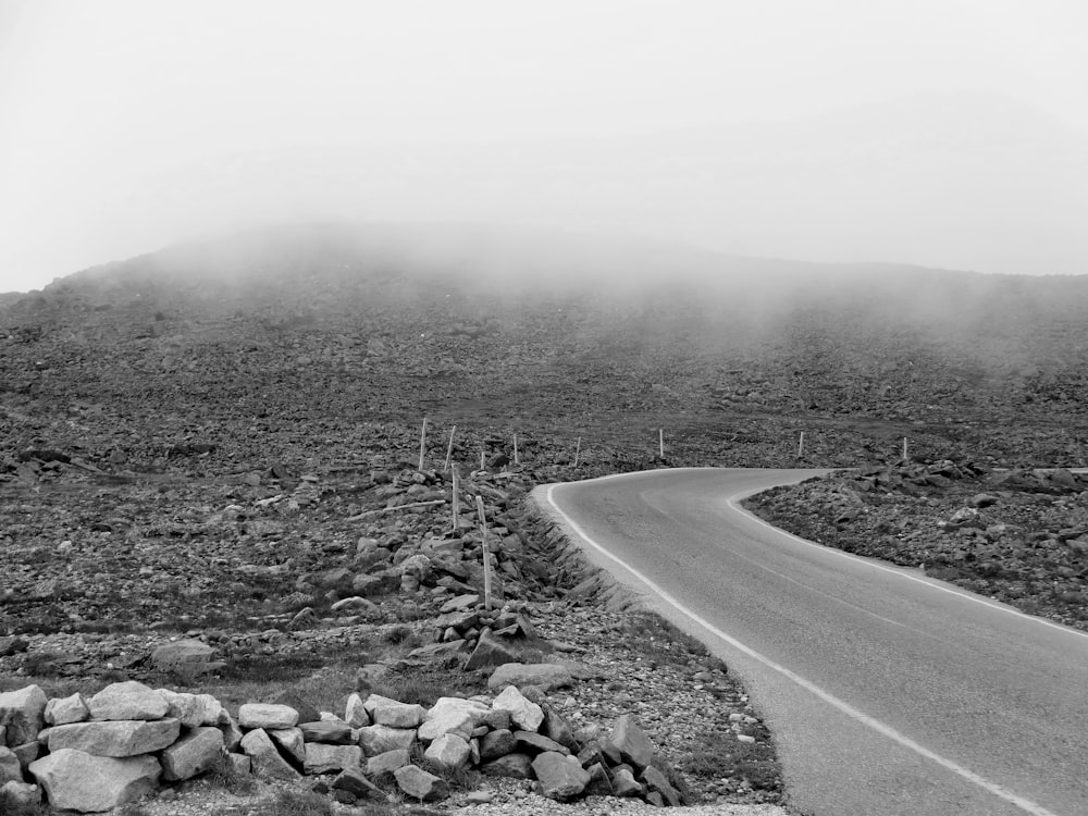 grayscale photo of road in the middle of grass field