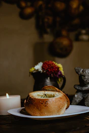 An intimate shot of a rustic wooden table set with a steaming bowl of soup and soft candlelight.
