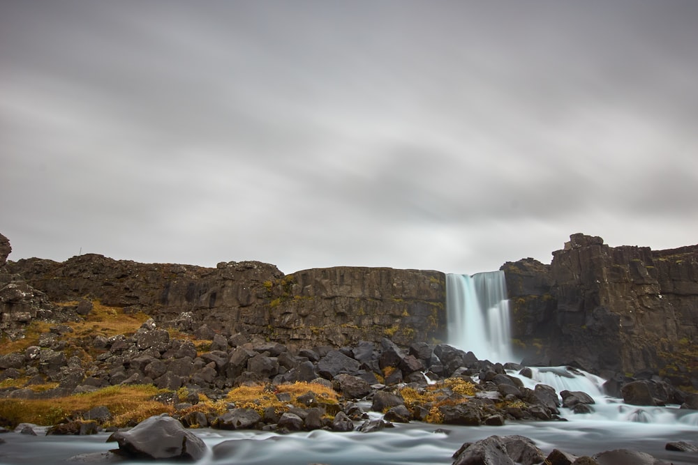 water falls under cloudy sky during daytime