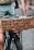A close-up shot of a bicycle with a cardboard sign attached to the back. The sign has a handwritten message that reads: 'Holes in our spirit cause in tears + fears one-sided stories, for years. Take the power.' The legs of a person in shorts are visible in the background.