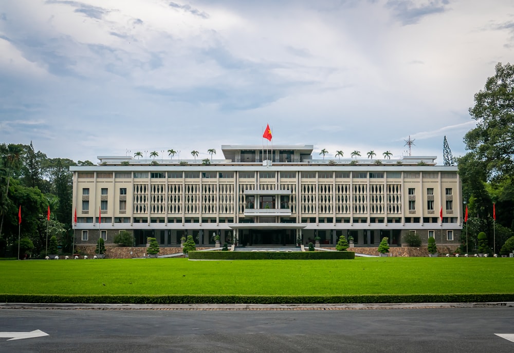 white concrete building with flag on top under white clouds during daytime