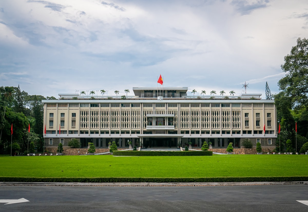 Ho Chi Minh City April — the green lawns and modernist facade of Reunification Palace in April heat, the last weeks before wet season