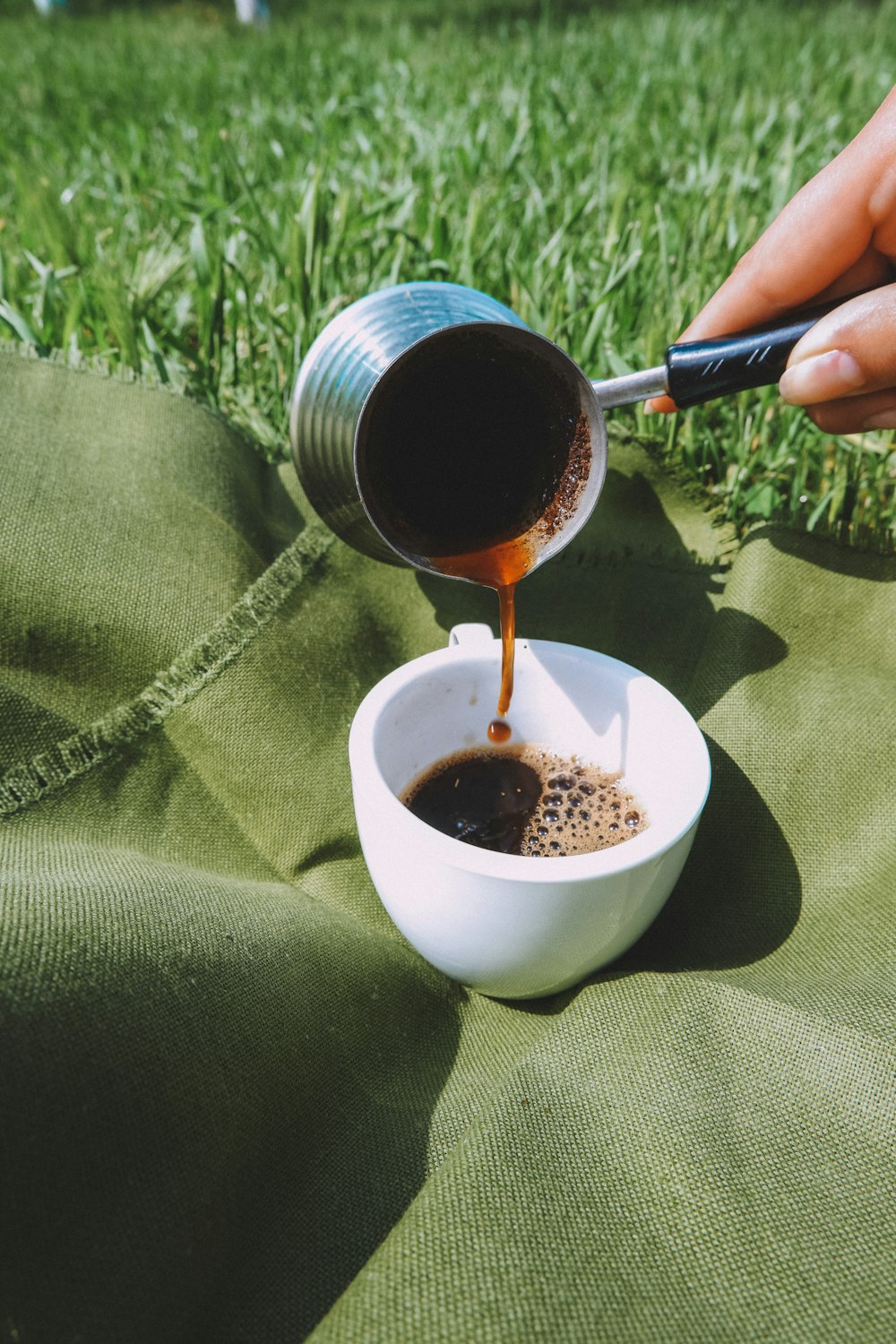 person pouring brown liquid on white ceramic mug