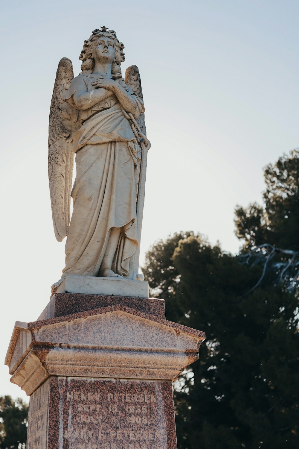 angel statue near green trees during daytime