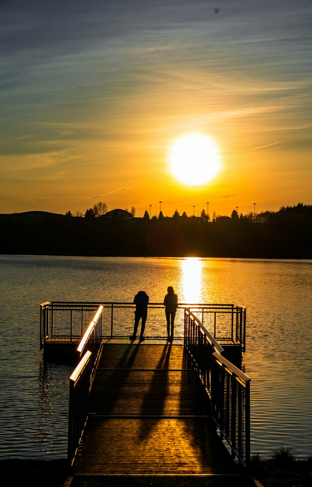 woman in black dress standing on dock during sunset