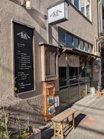 A matte forest green signboard with crisp lettering hanging outside a local artisanal restaurant.