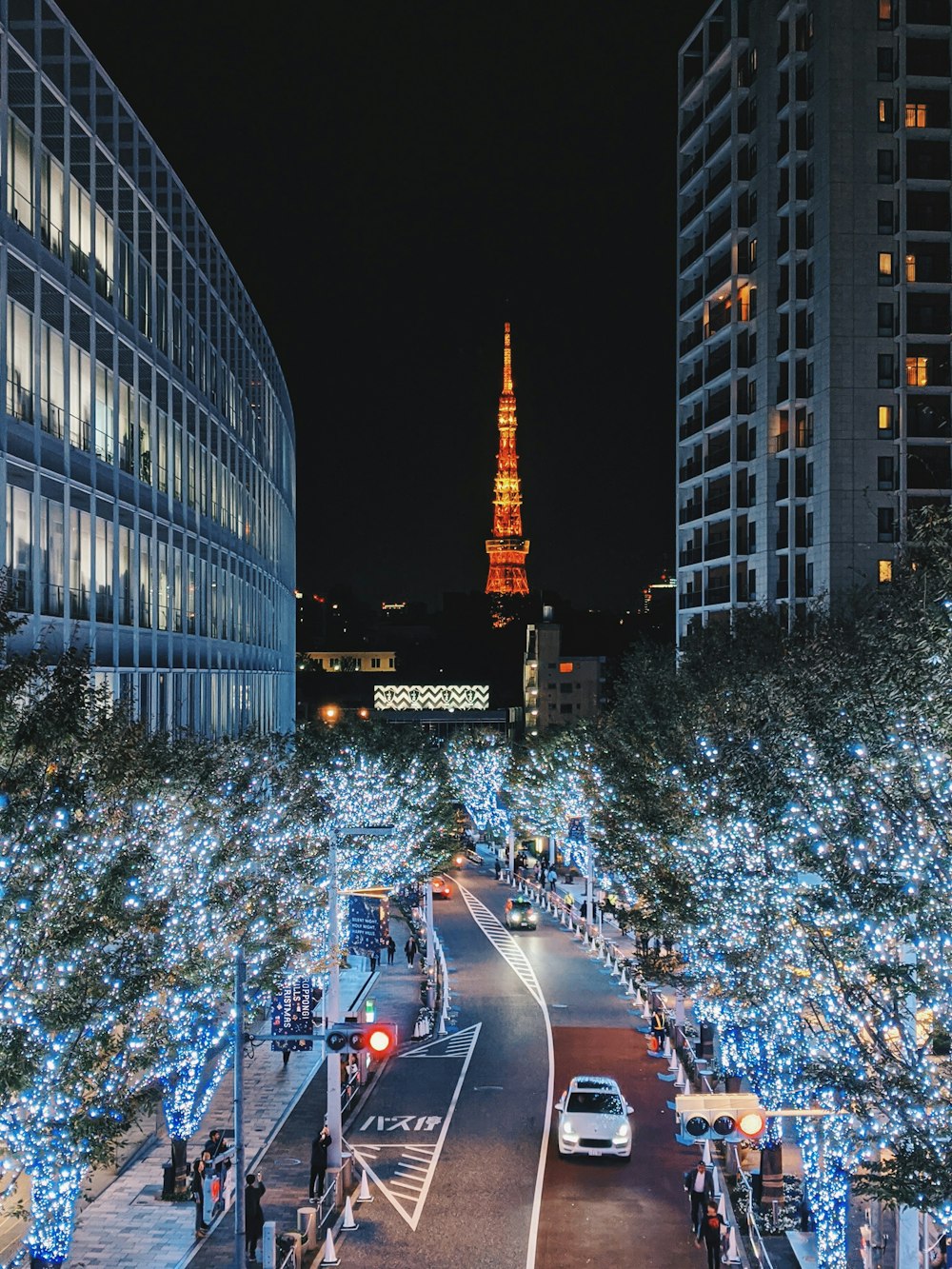 夜間に高層ビルの近くの道路を走る車