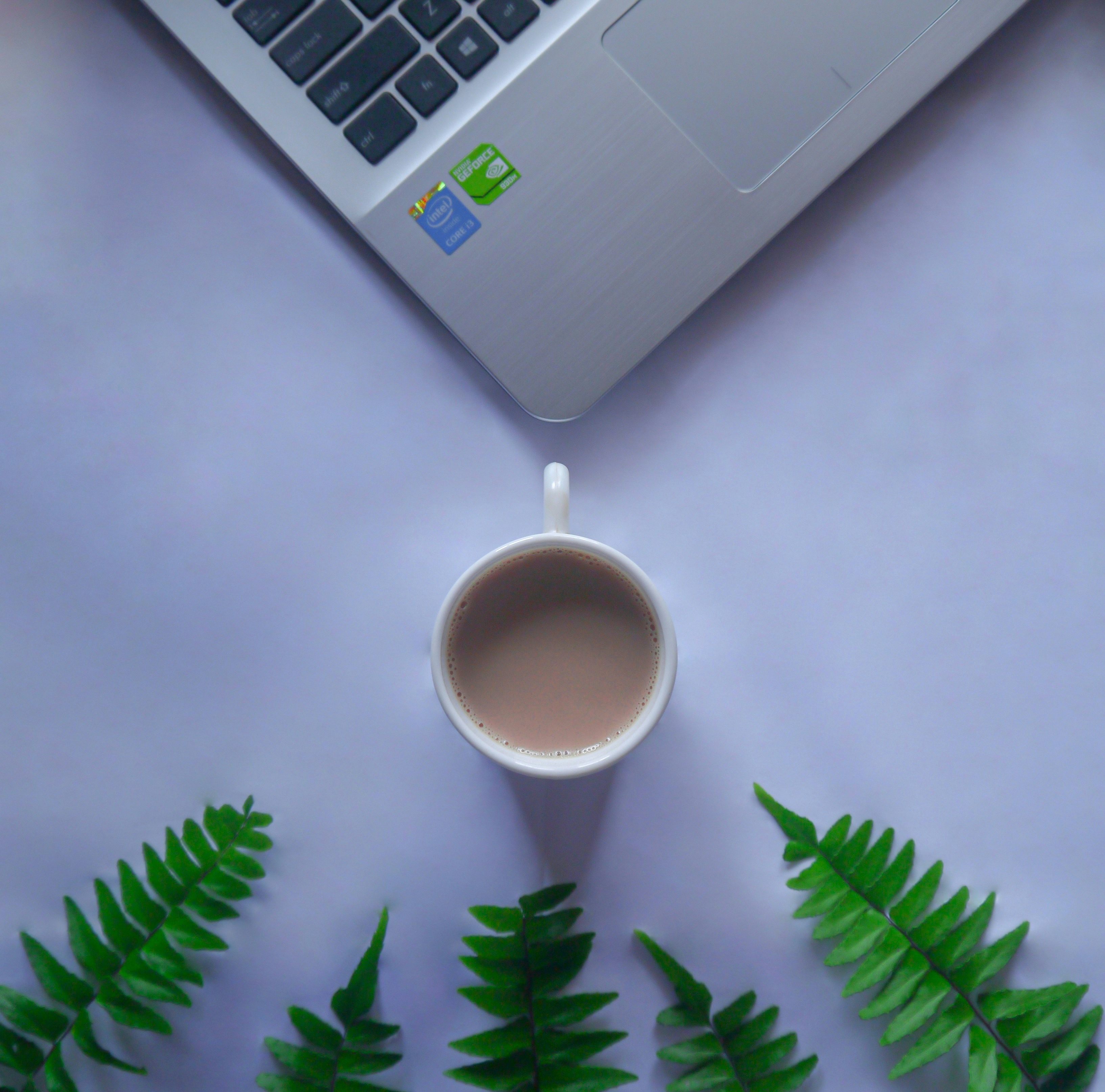 white ceramic mug beside macbook pro
