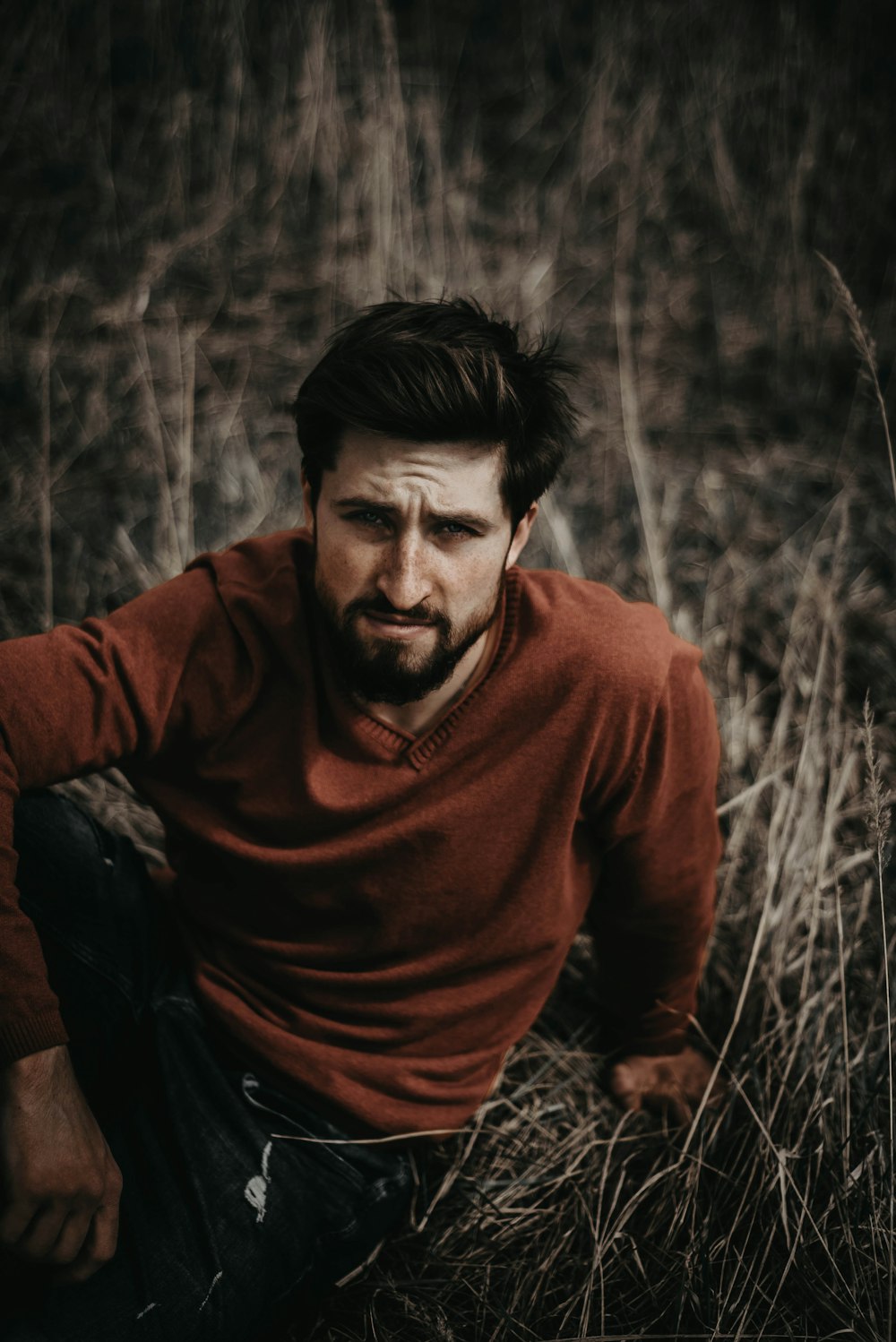 man in brown sweater sitting on brown grass during daytime