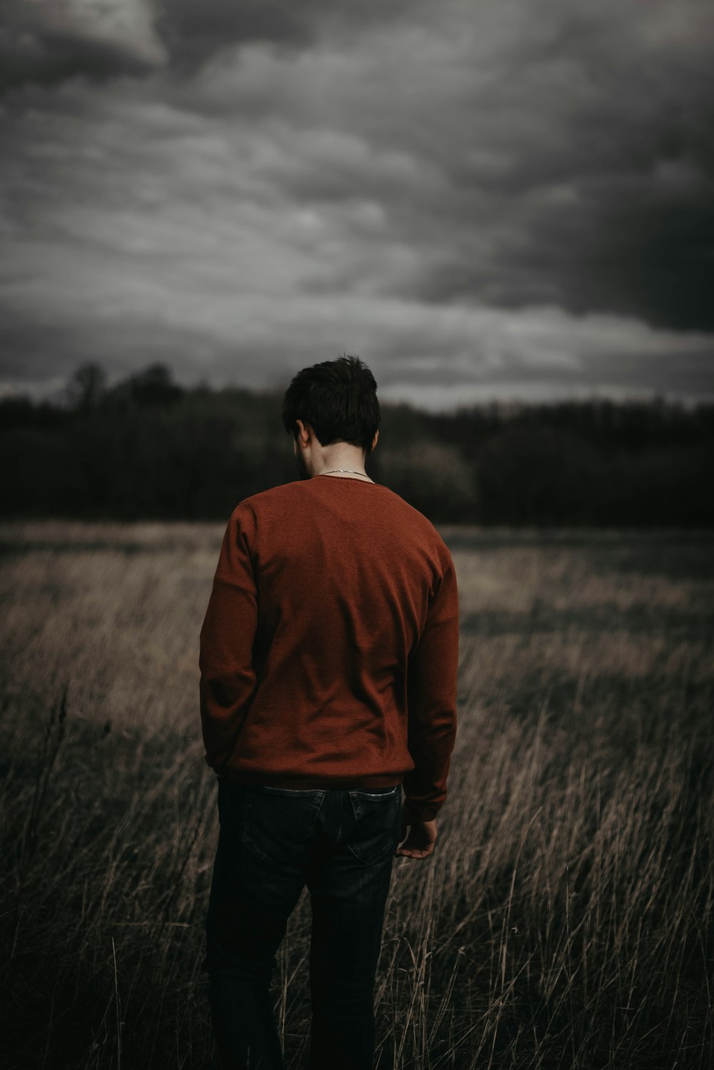 man in brown long sleeve shirt standing on green grass field during daytime