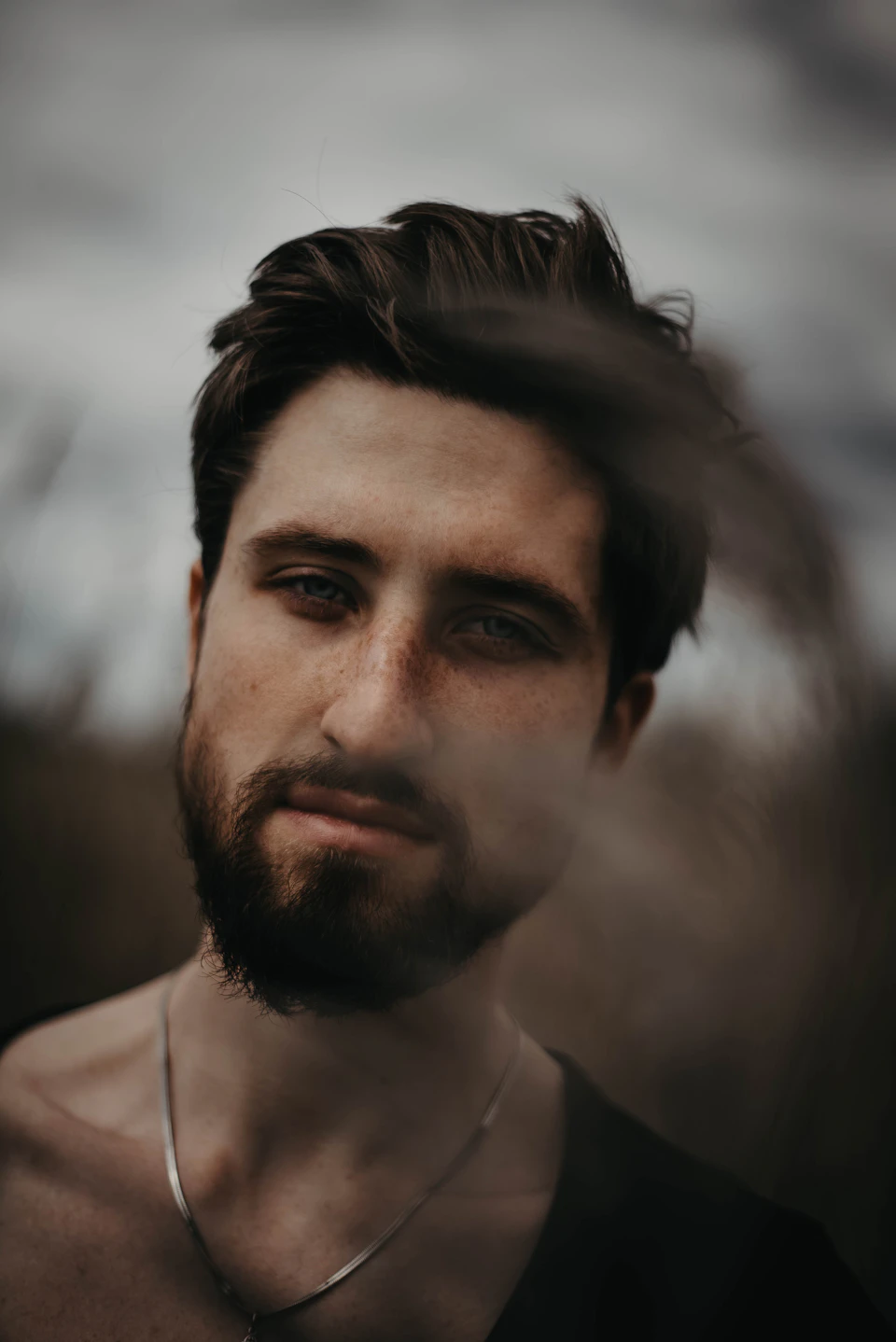 Young man with beard and short hair looks directly at the camera intensely