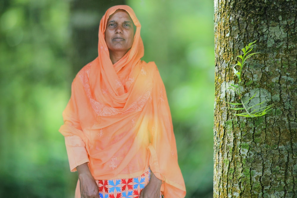 woman in orange hijab standing beside tree