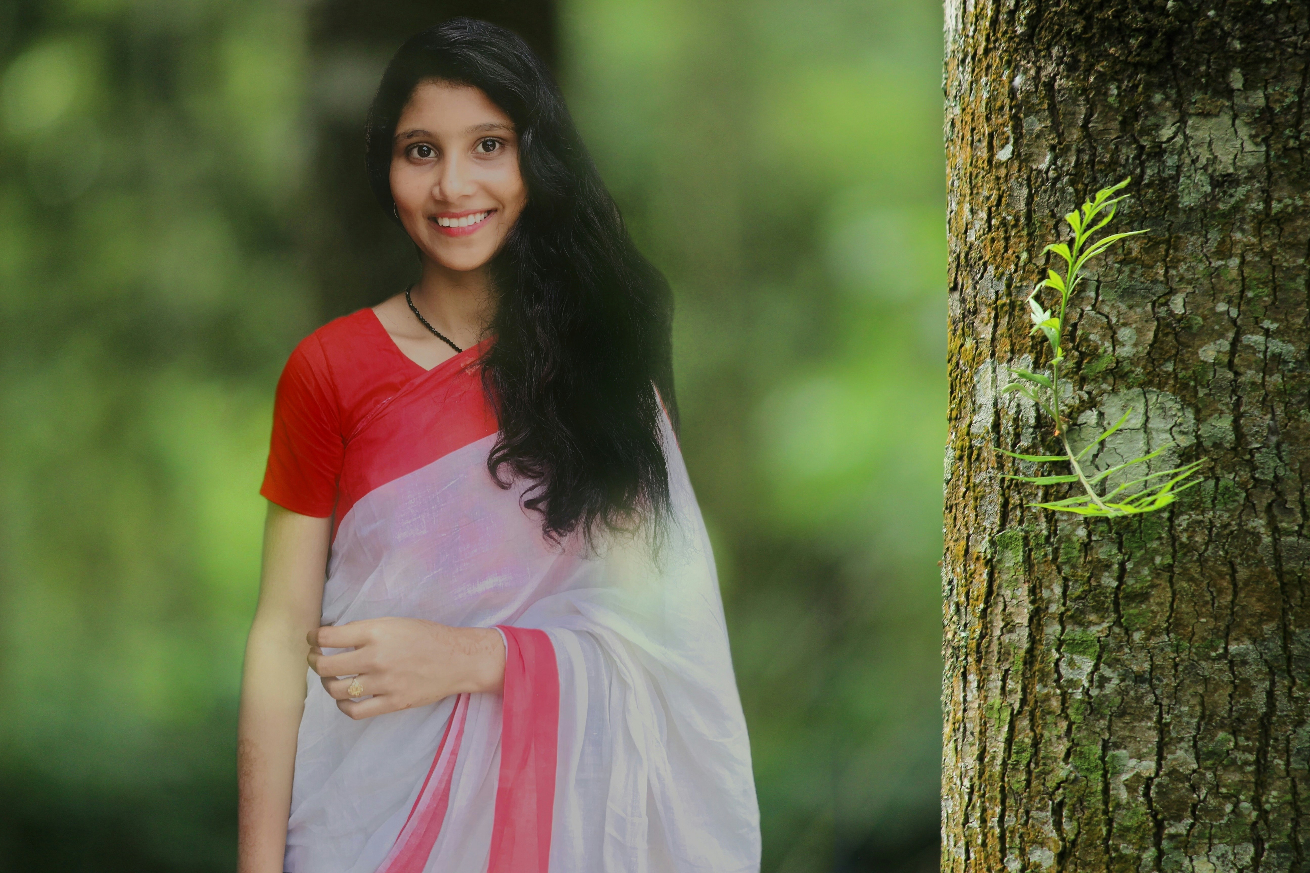 woman in red and white dress standing beside tree