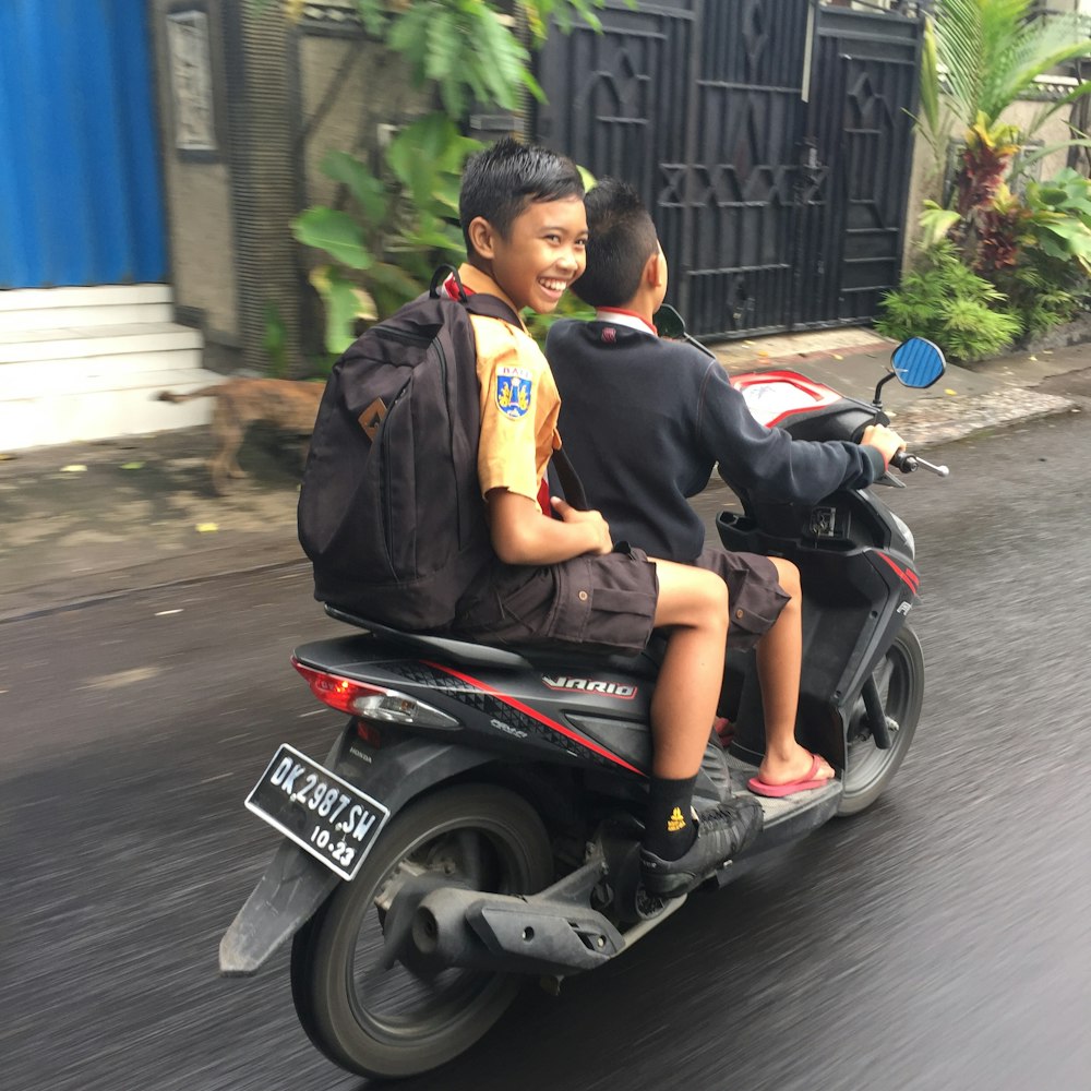 man in black and yellow polo shirt riding on black and red motorcycle during daytime