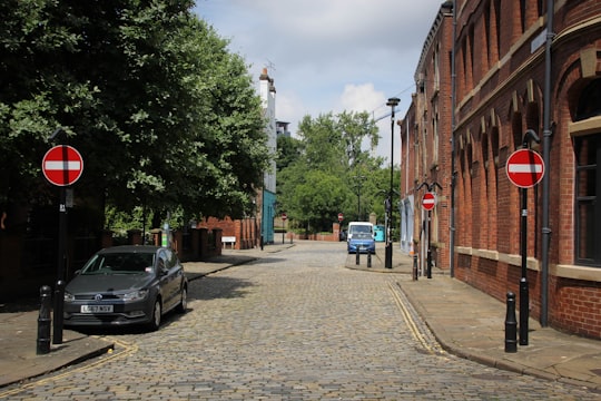 cars parked on sidewalk near buildings during daytime in Leeds United Kingdom