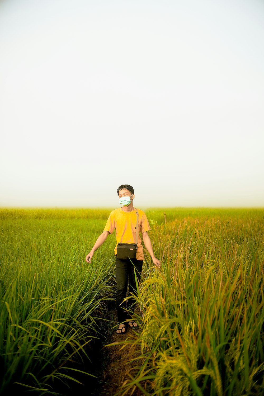 Uomo in maglietta girocollo gialla in piedi sul campo di erba verde durante il giorno