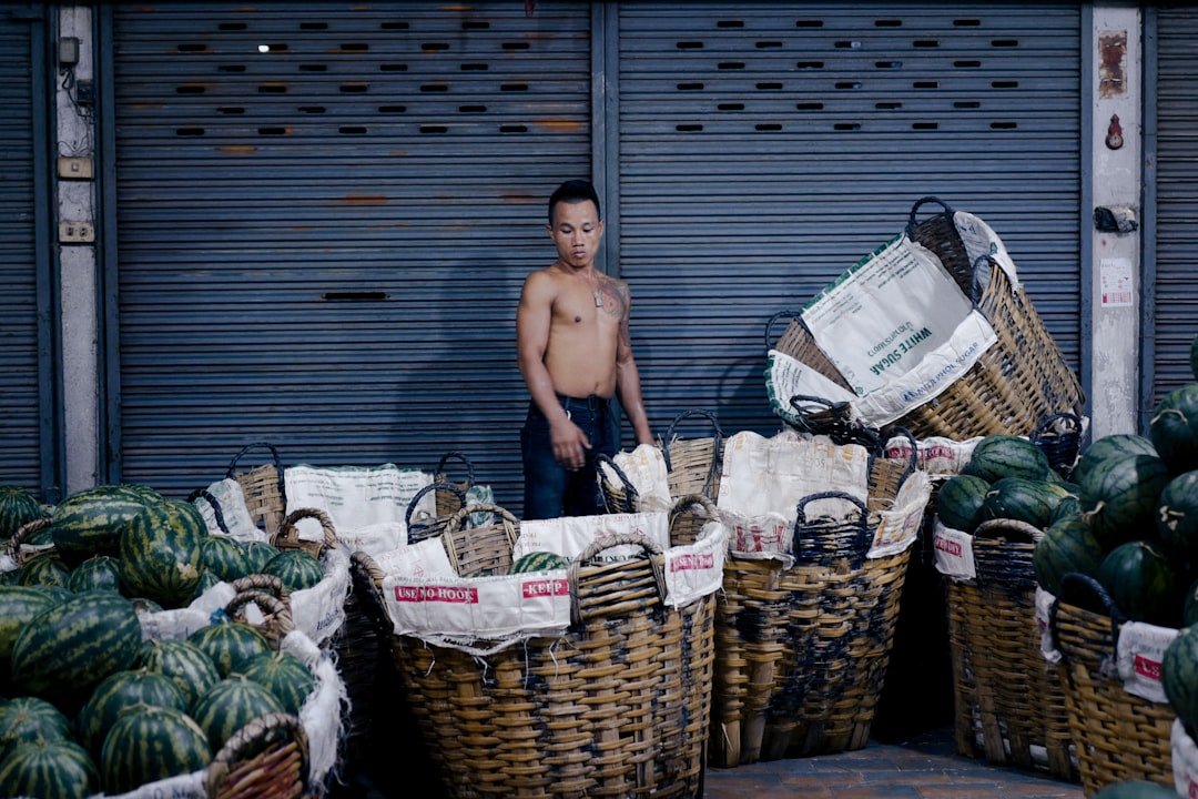 topless man in blue denim shorts standing beside brown woven baskets