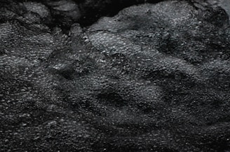 Dark, bubbling water with a textured, foamy surface creates a dynamic and somewhat mysterious appearance.