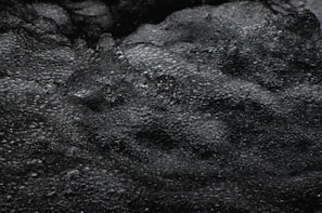 Dark, bubbling water with a textured, foamy surface creates a dynamic and somewhat mysterious appearance.