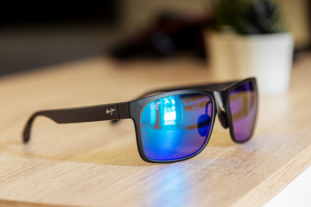 blue framed sunglasses on brown wooden table