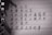 A close-up image of handwritten Chinese characters on lined paper with torn edges. The lighting casts shadows on the paper.