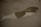 A puddle on an asphalt surface reflects part of a building, possibly a domed structure, in murky water. The pavement appears worn with visible cracks.