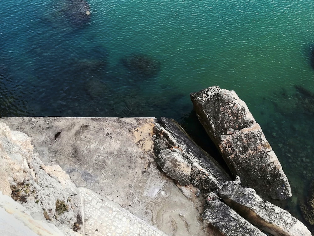 gray rock formation beside body of water during daytime