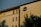 A residential building with a modern architectural design featuring rectangular windows and a distinctive circular window on the upper floor. The facade is illuminated by warm sunlight, casting shadows of nearby trees across the wall.