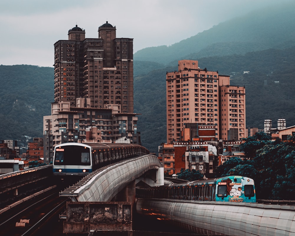 white and black train on rail near city buildings during daytime