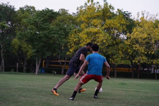 2 men playing soccer on green grass field during daytime