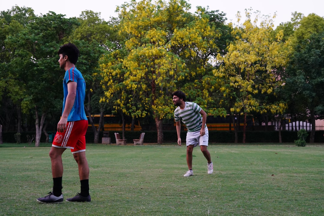 2 boys playing soccer on green grass field during daytime