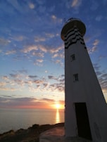 Historic lighthouse standing tall against a dramatic sunset on the Atlantic coast.