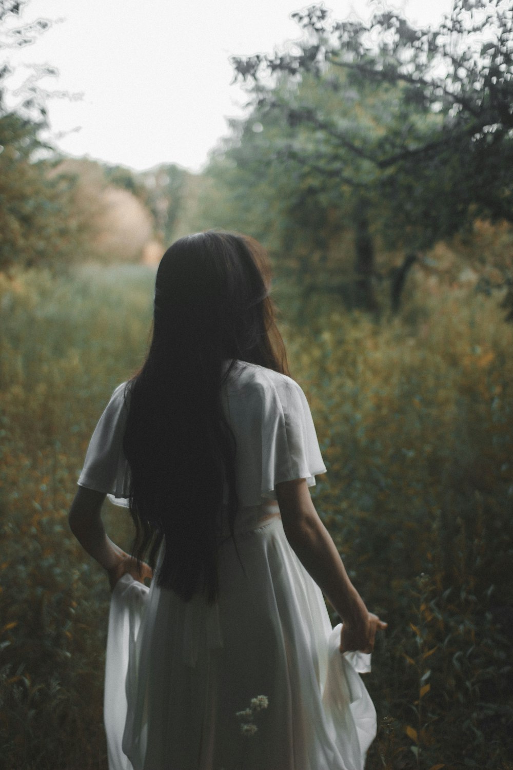 woman in white dress standing on forest during daytime