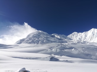 A cinematic shot of a majestic mountain range under a deep blue sky, with a luxury lodge nestled in the valley.
