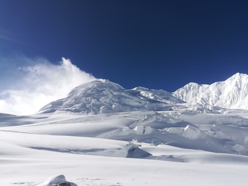 A cinematic shot of a majestic mountain range under a deep blue sky, with a luxury lodge nestled in the valley.