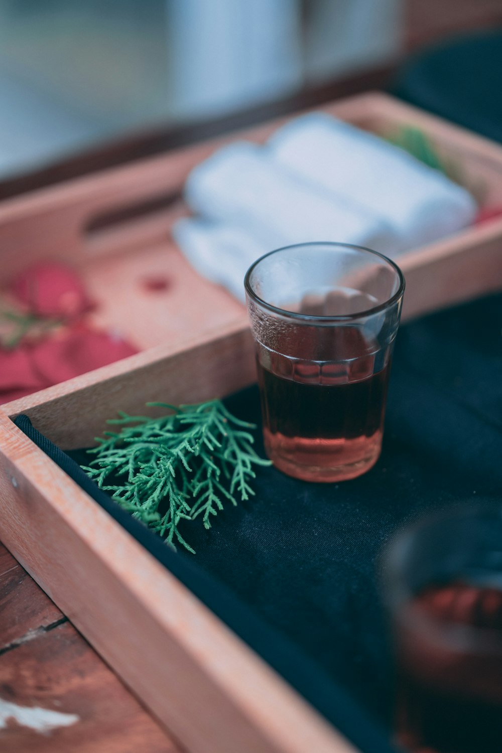 clear drinking glass with brown liquid on brown wooden tray