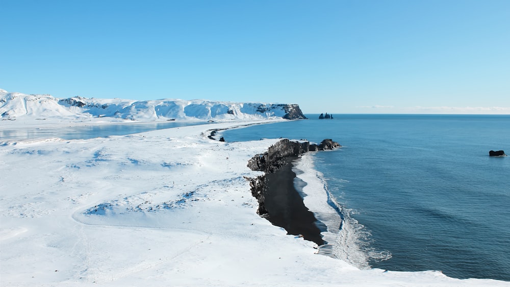 snow covered mountain near body of water during daytime