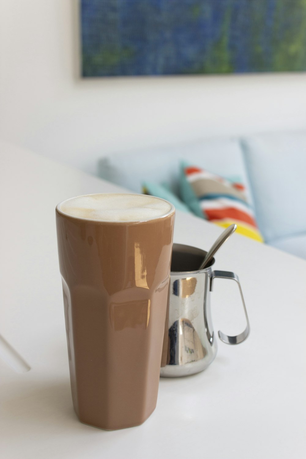 Taza de cerámica marrón y blanca sobre mesa blanca