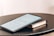 A tablet displaying a document is placed on top of a closed book. Both items rest on a round black table. The document on the tablet screen appears to be text-based, possibly an article or notes.