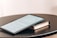 A tablet displaying a document is placed on top of a closed book. Both items rest on a round black table. The document on the tablet screen appears to be text-based, possibly an article or notes.