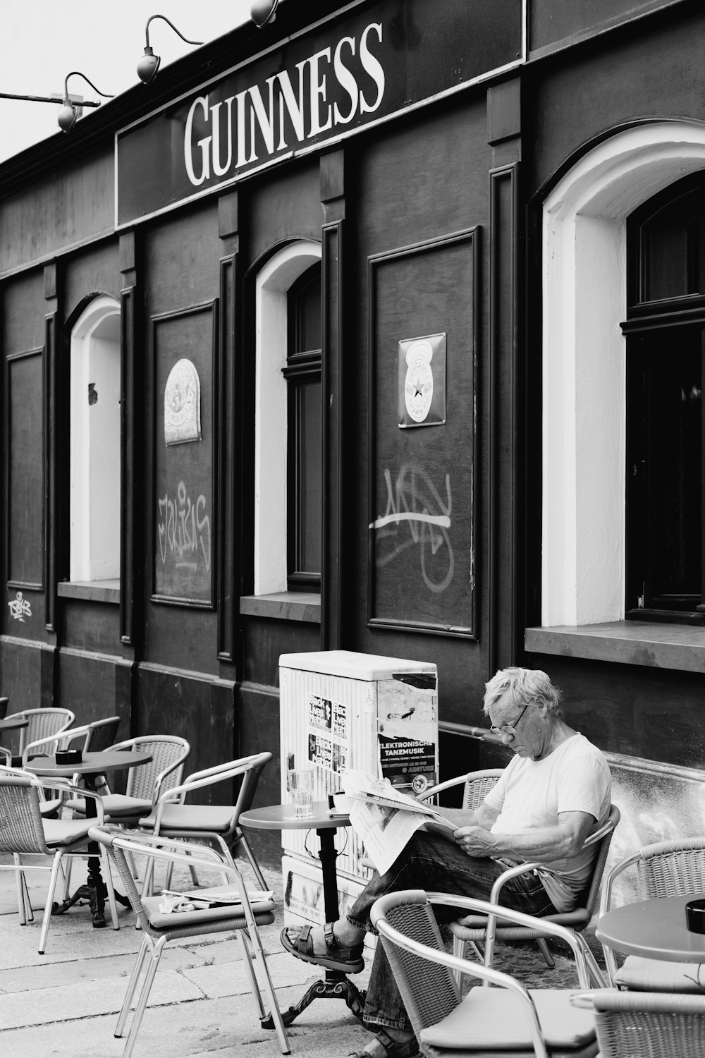Mann im weißen Hemd sitzt auf dem Stuhl und liest Zeitung
