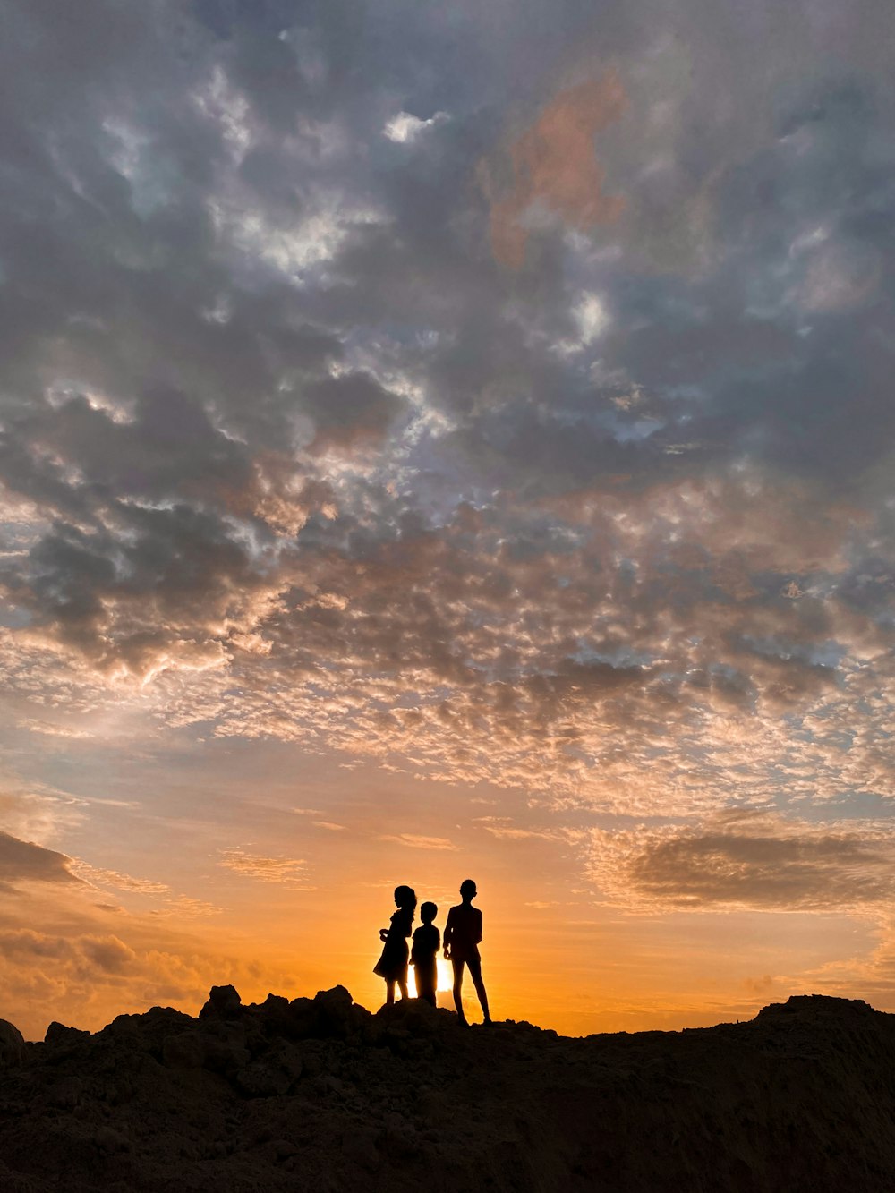silhouette of people standing on mountain during sunset